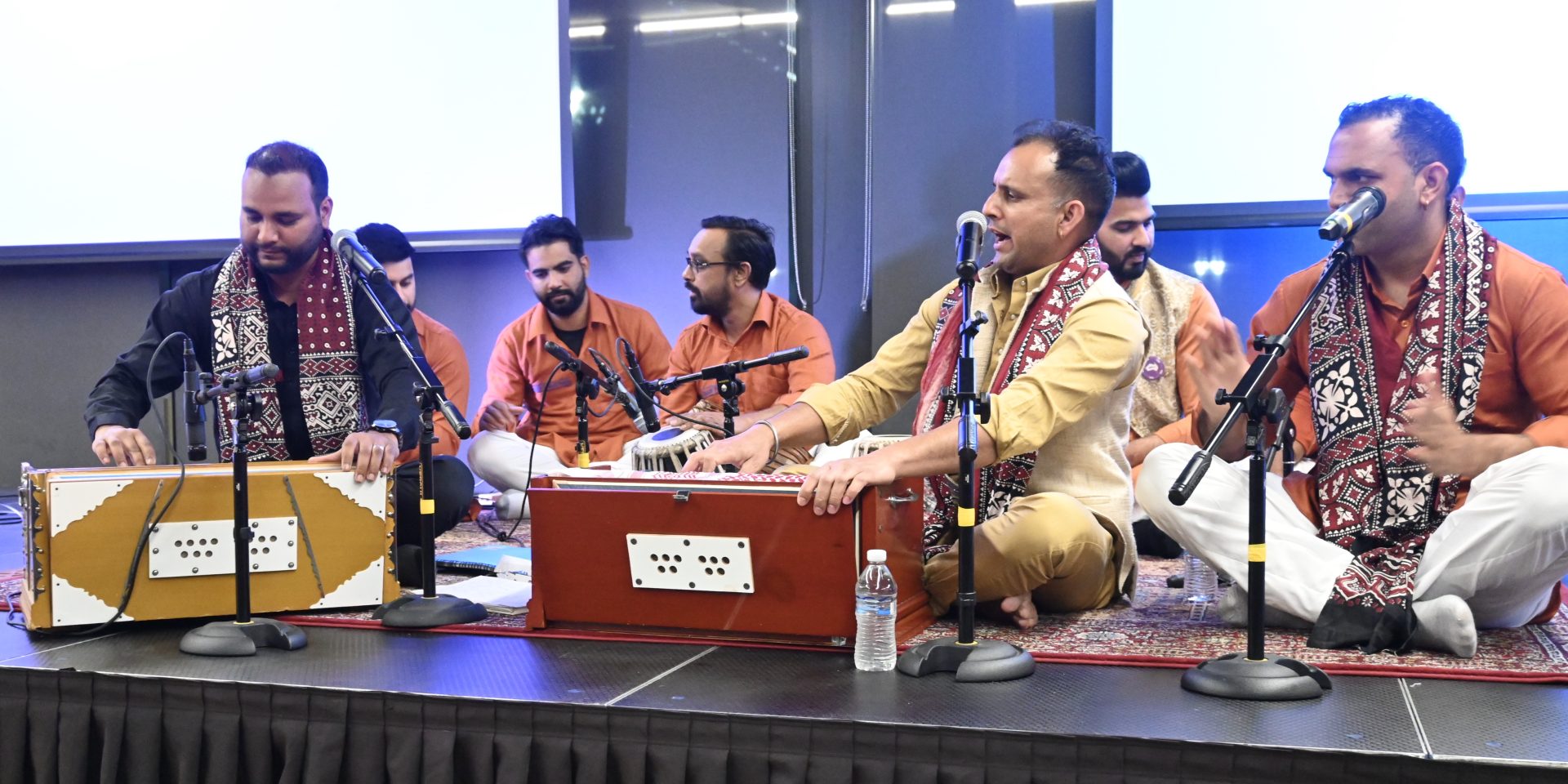 A group of men playing traditional South Asian musical instruments in Indian garb.