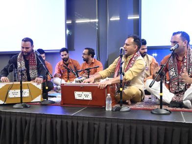 A group of men playing traditional South Asian musical instruments in Indian garb.